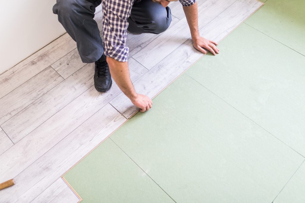 Worker installing bright laminated flooring boards, showing a smooth and vibrant floor surface